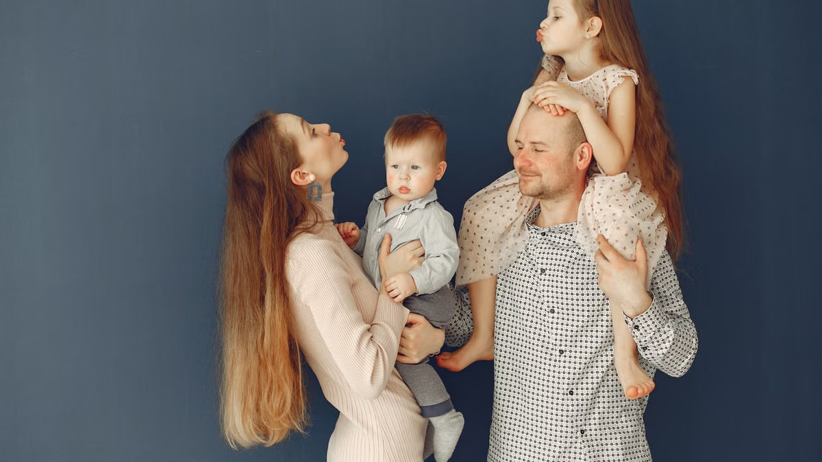 Portrait of a joyful family with parents and kids showing love and affection against a blue background.