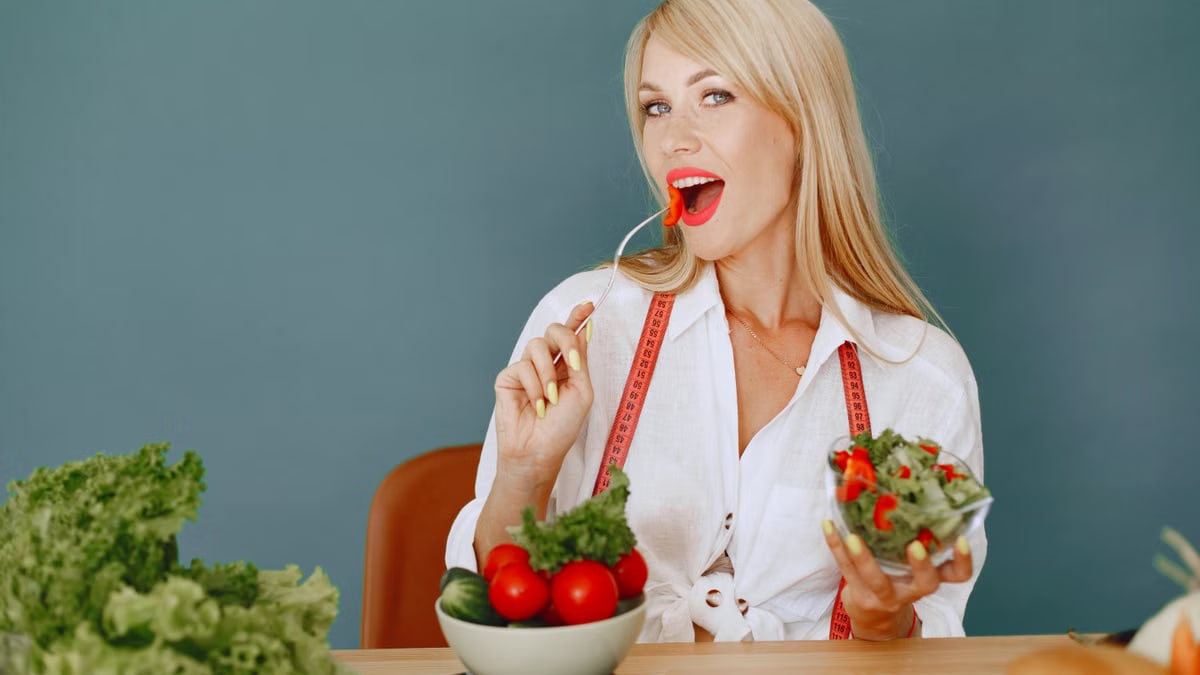 Woman enjoying a fresh salad with tomatoes and greens, promoting healthy eating.